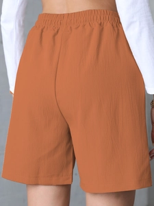 Rear view of orange linen shorts showing elastic waistband and loose wide-leg cut