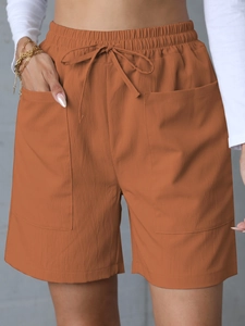Detail of caramel high-waist linen shorts featuring elastic drawstring and square pockets