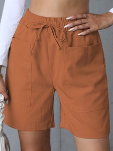 Detail of high waist orange linen shorts with elastic drawstring and large side pockets