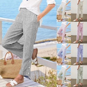 Detail of loose striped trousers with elastic waist and buttoned ankle hem decorations
