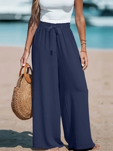 Dettaglio dei pantaloni a gamba larga a vita alta con elastico e fiocco sulla spiaggia
