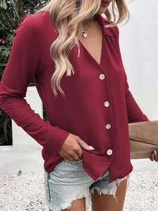 Detail showing the natural wood texture buttons and V-neckline of the wine red shirt