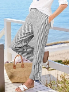Detail of black and white striped trousers with white decorative buttons at the side hem