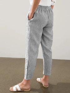 Detail of vertical striped loose trousers featuring elastic waist and buttoned side hem