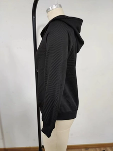 Détail d'un sweat à capuche noir avec texture tricotée à motifs géométriques en relief