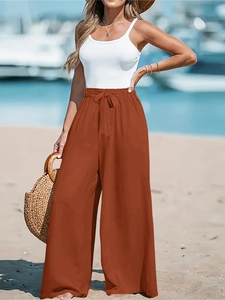 Dettaglio dei pantaloni larghi rosso ruggine a vita alta con elastico e fiocco alla moda