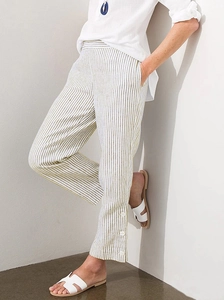 Close-up of olive green striped cotton linen pants featuring button details at the hem