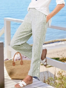 Detail of green striped summer trousers with decorative buttons at the side ankles