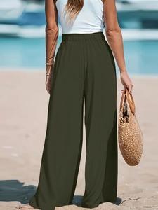 Vista posteriore dei pantaloni a vita alta gamba larga verde oliva in tessuto leggero sulla spiaggia