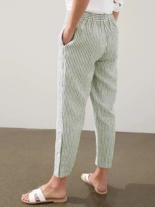 Close-up of green vertical striped linen pants with white button details on the leg hem