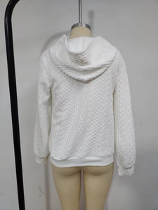 Detail view of white cable knit texture and hooded design on a long-sleeve sweater