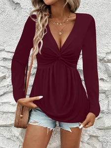 Detail of burgundy V-neck top with front twist knot design and soft pleated hemline