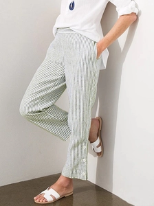 Detail of green and white striped casual pants with side buttons and linen texture