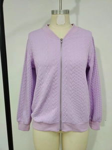 Détail de la veste en maille violette avec torsades à l'avant et manches matelassées