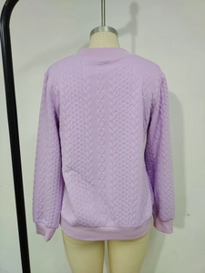 Détail du haut en maille lavande présentant des motifs torsadés et gaufrés complexes
