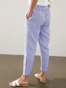 Close-up of blue and white striped trousers featuring elastic waist and side button detail