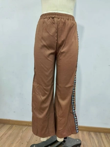 Detail einer braunen Hose mit hohem Bund und seitlicher ethnischer Blumenstickerei