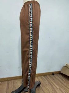 Detail der braunen Hose mit hoher Taille und geometrischer Stickerei an der Seitennaht
