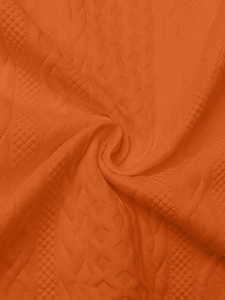 Detailed macro view of orange cable knit fabric with intricate braided textures