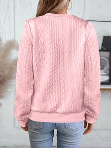 Détail de la vue arrière d'un pull en maille torsadée rose clair avec bords côtelés