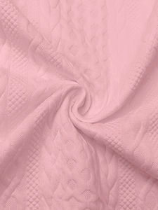 Close-up of pink waffle knit fabric with intricate cable textures and soft fibers