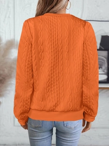 Détail du dos d'une veste en maille orange avec texture torsadée et bordure côtelée