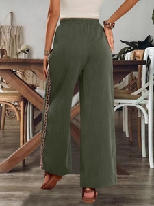 Detail der ethnischen Webstreifen an der olivgrünen weiten Hose im Boho-Stil