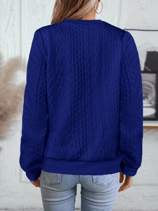 Détail de la maille torsadée bleu marine et des poignets côtelés sur le cardigan
