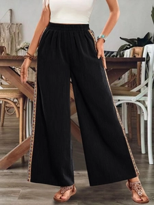Detail der ethnischen Stickerei an schwarzer Weithals-Hose im lässigen Boho-Stil