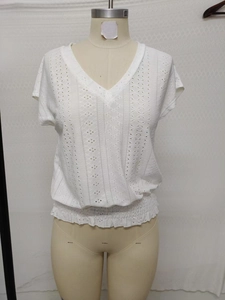Detail of white V-neck top showing delicate eyelet embroidery and elasticated waist hem