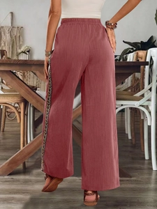 Nahaufnahme der weiten Hose mit ethnisch bunt gewebtem Band an den Seitennähten