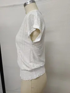 Detail of white V-neck hollow embroidery T-shirt featuring smocked waist and eyelet pattern