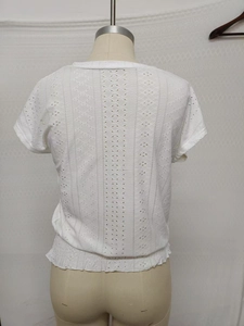 Detail of white eyelet lace top with hollow embroidery and elastic ruffled hemline