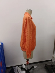 Close-up of orange zip-up sweatshirt with quilted diamond texture and ribbed cuffs