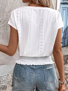 Detail of white hollow embroidered V-neck top with elastic waist and ruffled hem