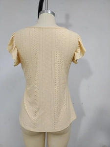 Detailed view of pale yellow eyelet embroidery fabric and layered ruffle sleeve design