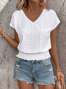 Detail of V-neck white blouse featuring intricate eyelet embroidery and a smocked hemline