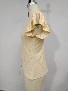 Detail of light yellow eyelet embroidery and flutter sleeves on a women's V-neck top