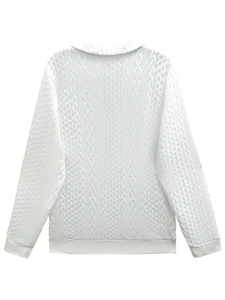 Detailed close-up of intricate white cable knit textures and patterns on sweater