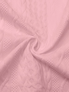 Detail of light pink knit fabric featuring 3D geometric texture and soft braided pattern