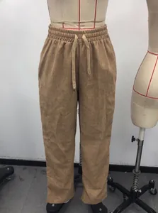 Detail of drawstring waist and corduroy texture on brown loose straight trousers