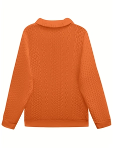 Detail of orange cable knit sweater with textured diamond patterns and ribbed hem