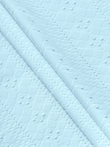 Detail of light blue eyelet lace fabric with geometric embroidery and hollow textures