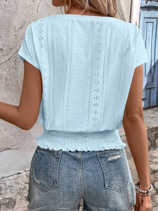 Detail of light blue short sleeve top featuring hollow lace embroidery and smocked waist