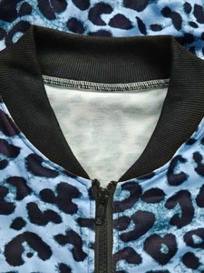 Detail of blue leopard print cardigan featuring a black ribbed collar and zipper closure