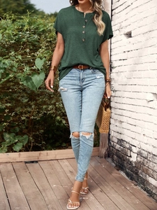 Detail of dark green Henley T-shirt with wooden buttons and light blue ripped jeans