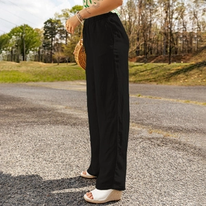 Detail of high-waisted black cotton linen wide-leg pants with elastic waist and side pockets