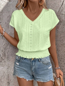 Detail of light green V-neck eyelet top featuring smocked waist and ruffle hem detail