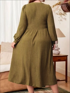 Detailed back view of an army green ribbed knit A-line dress in a cozy indoor setting