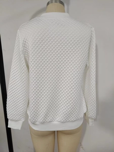 Detail view of the quilted diamond pattern and ribbed hem on the white bomber jacket